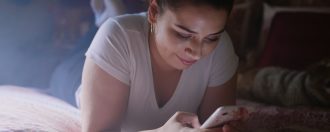 Girl on mobile phone laying on bed