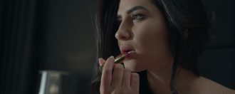 Girl putting on lipstick in music video